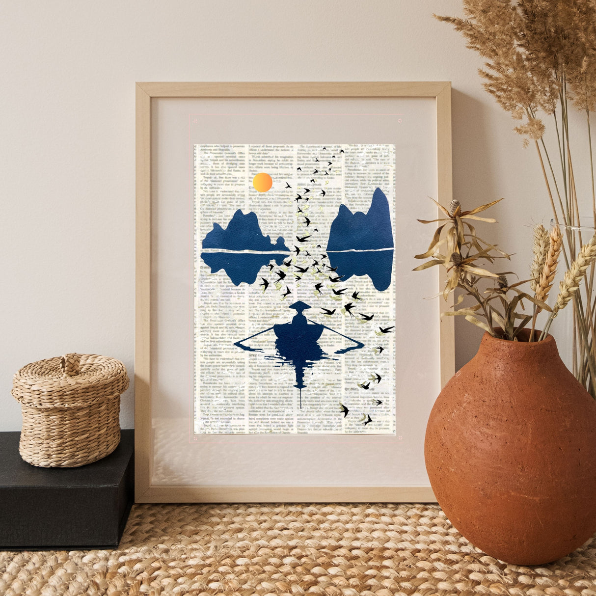 Tableau Hanoï créé avec le pochoir artistique Panash Art, peint sur une page de journal et encadré dans une décoration naturelle avec vase en terre cuite et panier tressé.