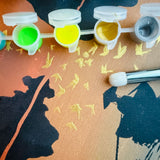 Détail du modèle Hanoï réalisé avec le pochoir artistique Panash Art.
On voit le pinceau, les godets de peinture jaune et or, et les oiseaux peints sur le fond coloré.