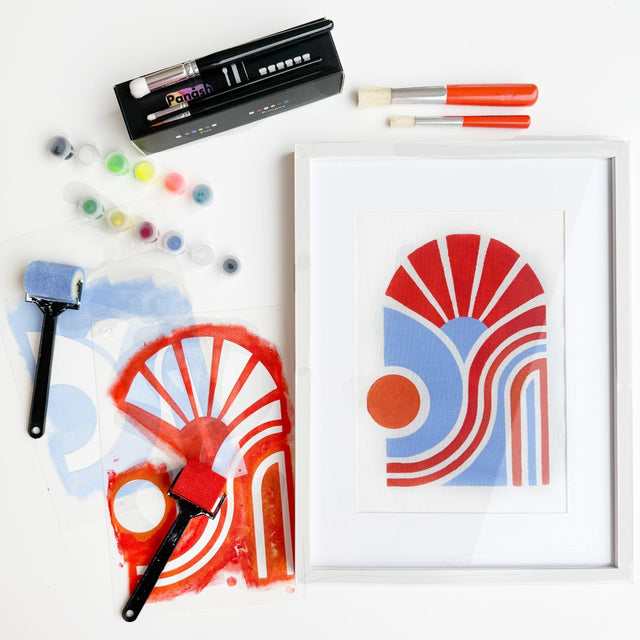 Vue de dessus d'une oeuvre bloom aura finie et les pochoirs a coté avec la box accessoires et peinture et les pinceaux